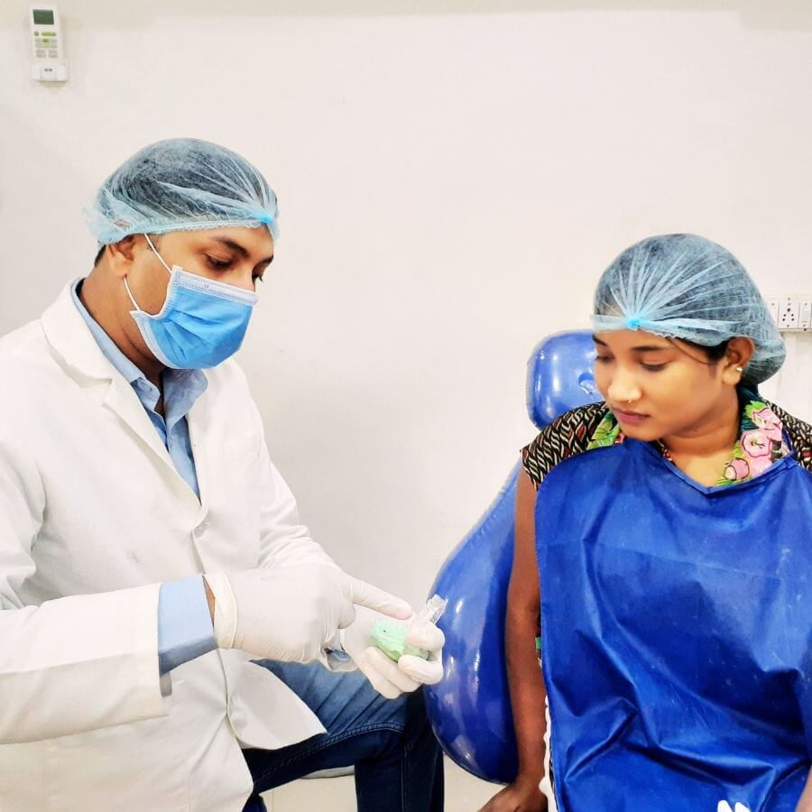 A dental professional in the field of prosthodontics is outlining the treatment procedures to a patient who is seated in the dental chair.