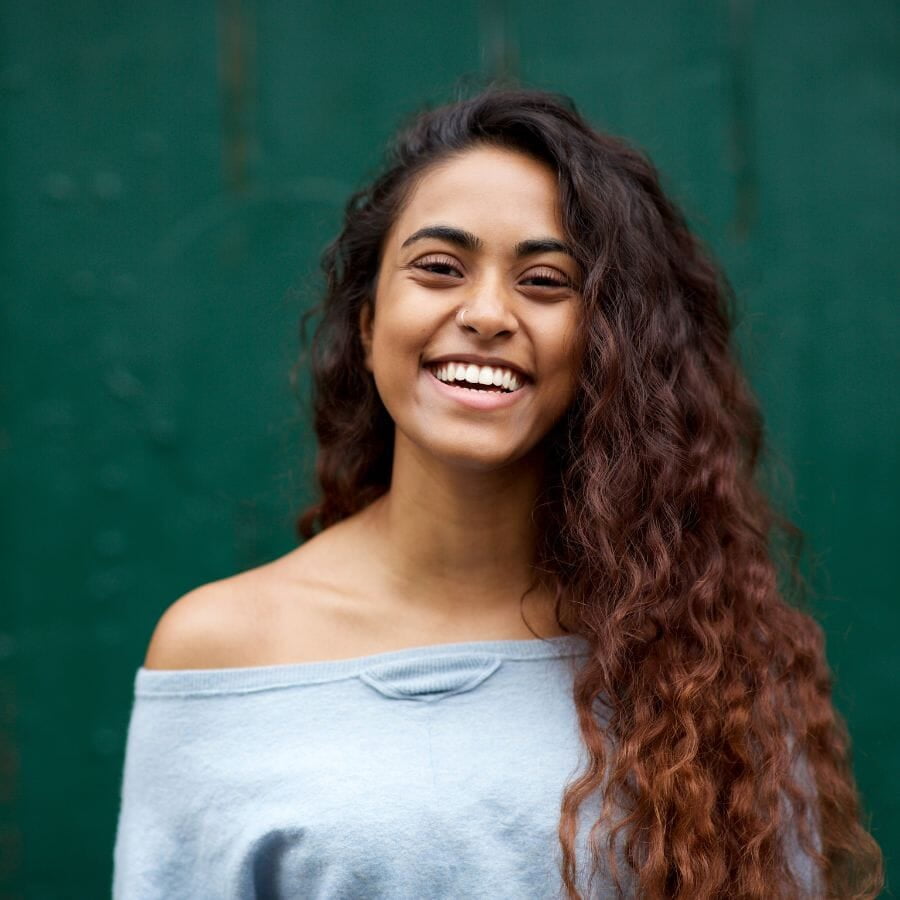 Women smiling with green background after orthodontic treatment.