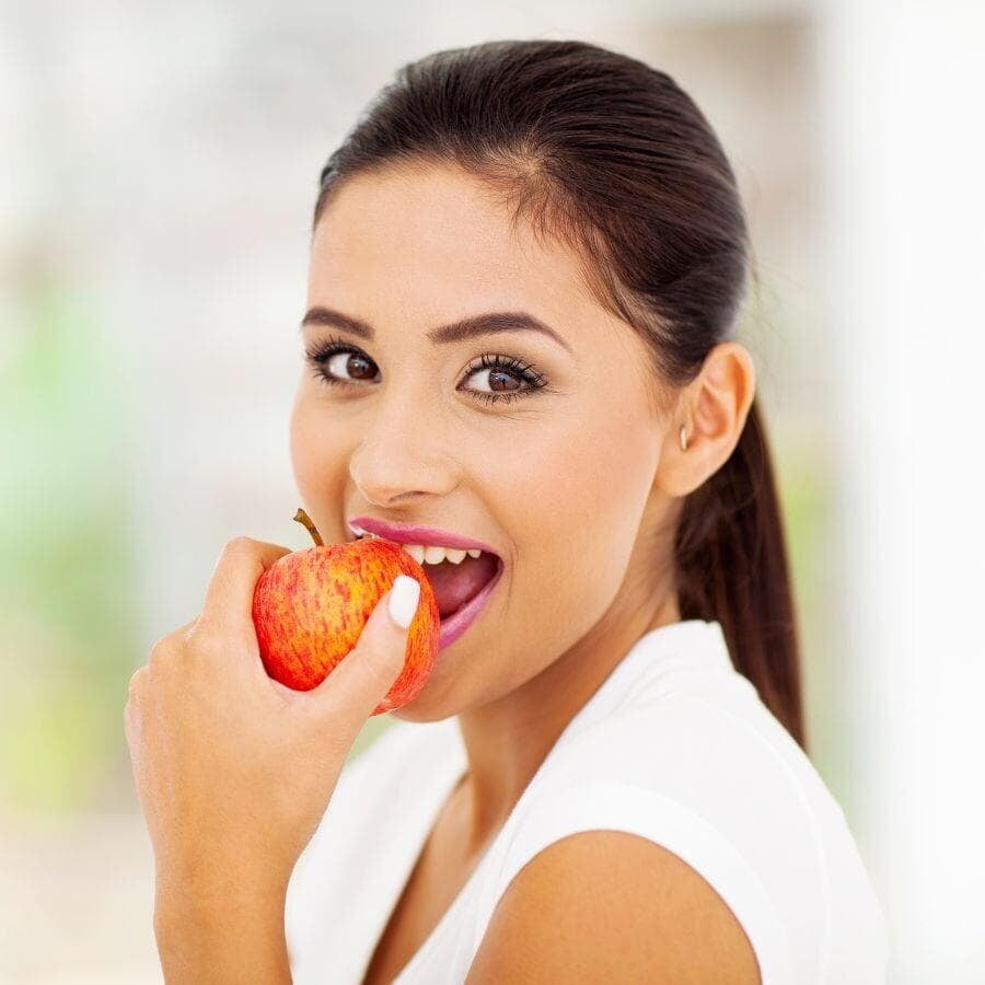 A woman eating apple showing enhanced chewing efficiency after orthodontist braces treatment